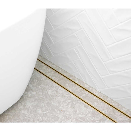 Close-up of a tiled floor with Lauxes Grates Custom shower drain Tile Insert in Matte Gold finish 