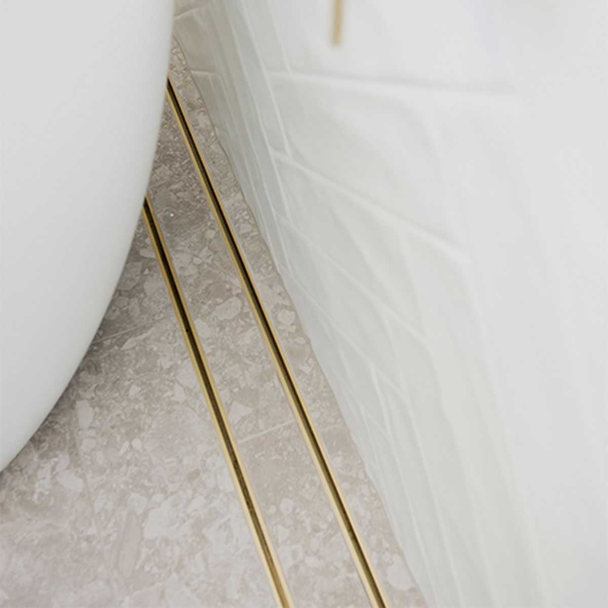 Close-up of a tiled floor with Lauxes Grates Custom shower drain Tile Insert in Matte Gold finish 
