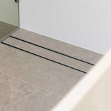 Close-up of a tiled floor with Lauxes Grates Custom shower drain Tile Insert in Silk Silver finish 