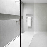 Modern bathroom with glass shower enclosure and towel rack with Close-up of a tiled floor with Lauxes Grates Custom shower drain Tile Insert in Silk Silver finish 
