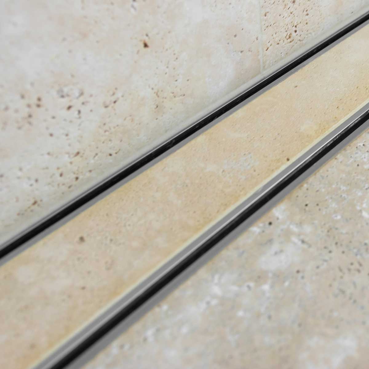 Close-up of a tiled floor with Lauxes Grates Custom shower drain Tile Insert in Silk Silver finish 