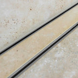 Close-up of a tiled floor with Lauxes Grates Custom shower drain Tile Insert in Silk Silver finish 