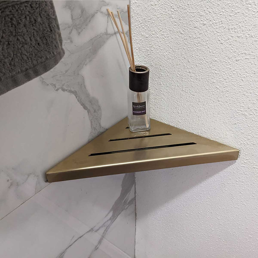 SereneDrains Stainless Steel Satin Gold Corner shower shelf mounted on a marble wall