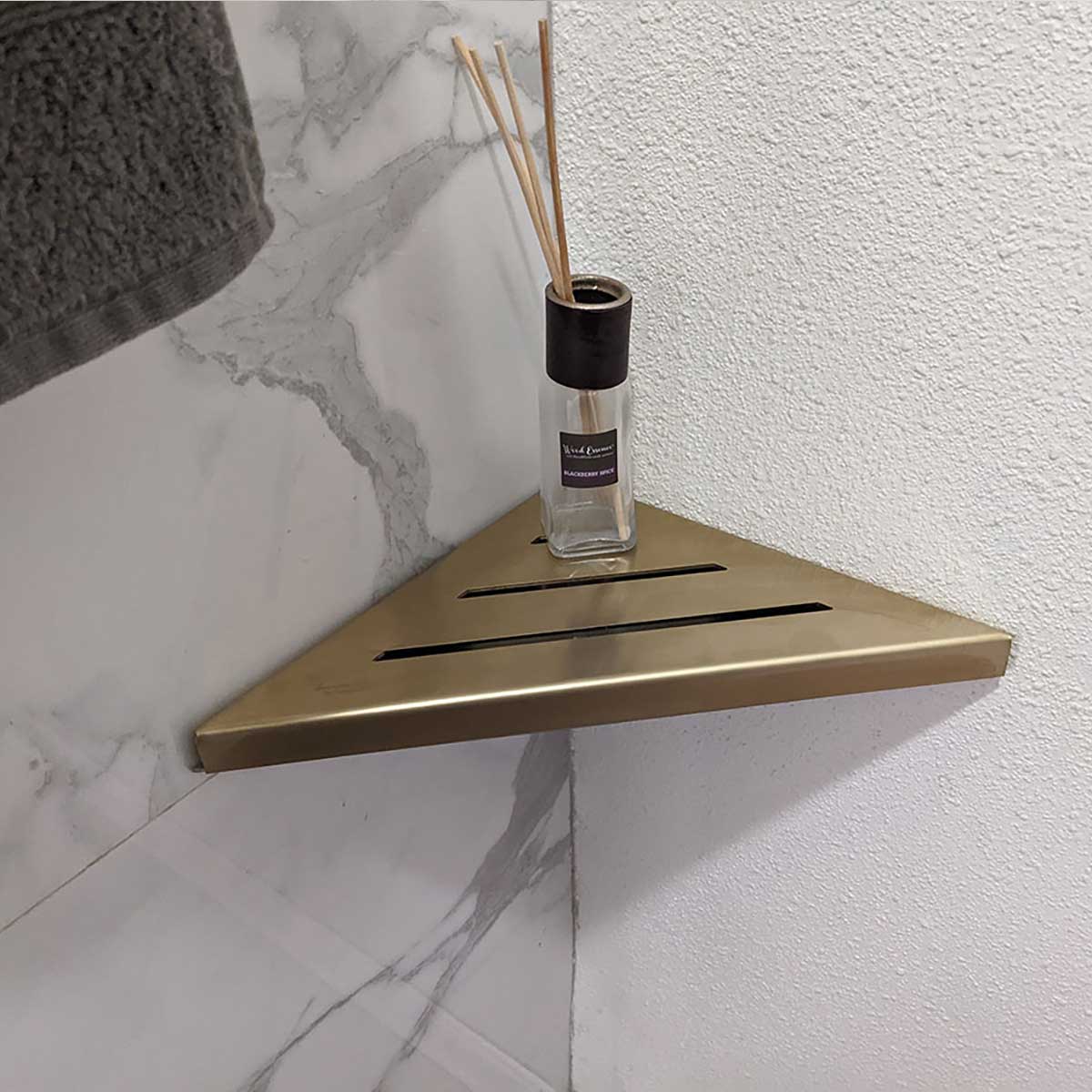 SereneDrains Stainless Steel Satin Gold Corner shower shelf mounted on a marble wall