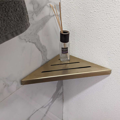 SereneDrains Stainless Steel Satin Gold Corner shower shelf mounted on a marble wall