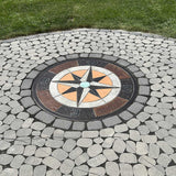 Smith Paint Colorful stains Decorative concrete mosaic compass design inlaid into a cobblestone patio surrounded by green grass.