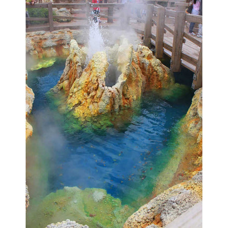 Colorful hot spring with steaming water and rocky formations, surrounded by wooden walkways.