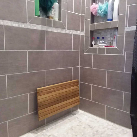 Wall mounted teak bench folded against shower wall