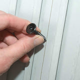 TI-ProBoard Head Deck Screw - Hand holding a black screw against a white wooden panel background