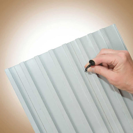 TI-ProBoard Head Deck Screw - Hand holding a pen on a corrugated metal sheet with a beige background