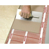 Warmup StickyMat applying a tile to a floor with Warmup heating cable visible underneath
