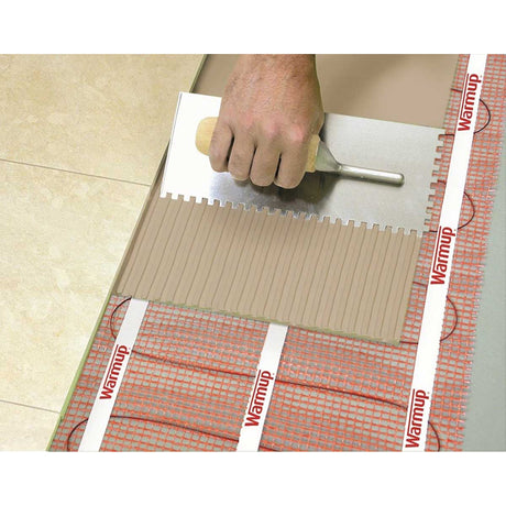 Warmup StickyMat applying a tile to a floor with Warmup heating cable visible underneath