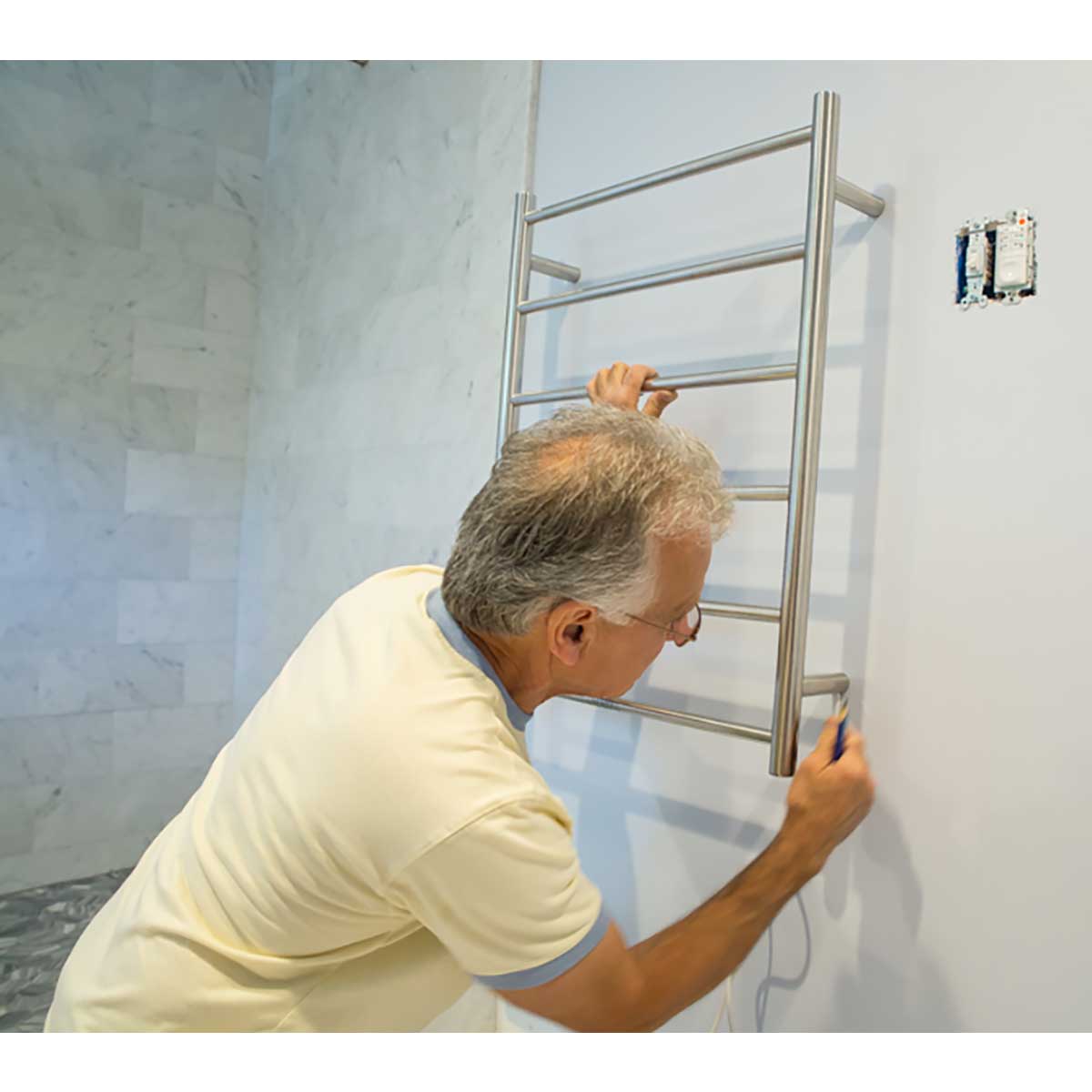 Person installing WarmUp Electric Towel Warmer on a wall.